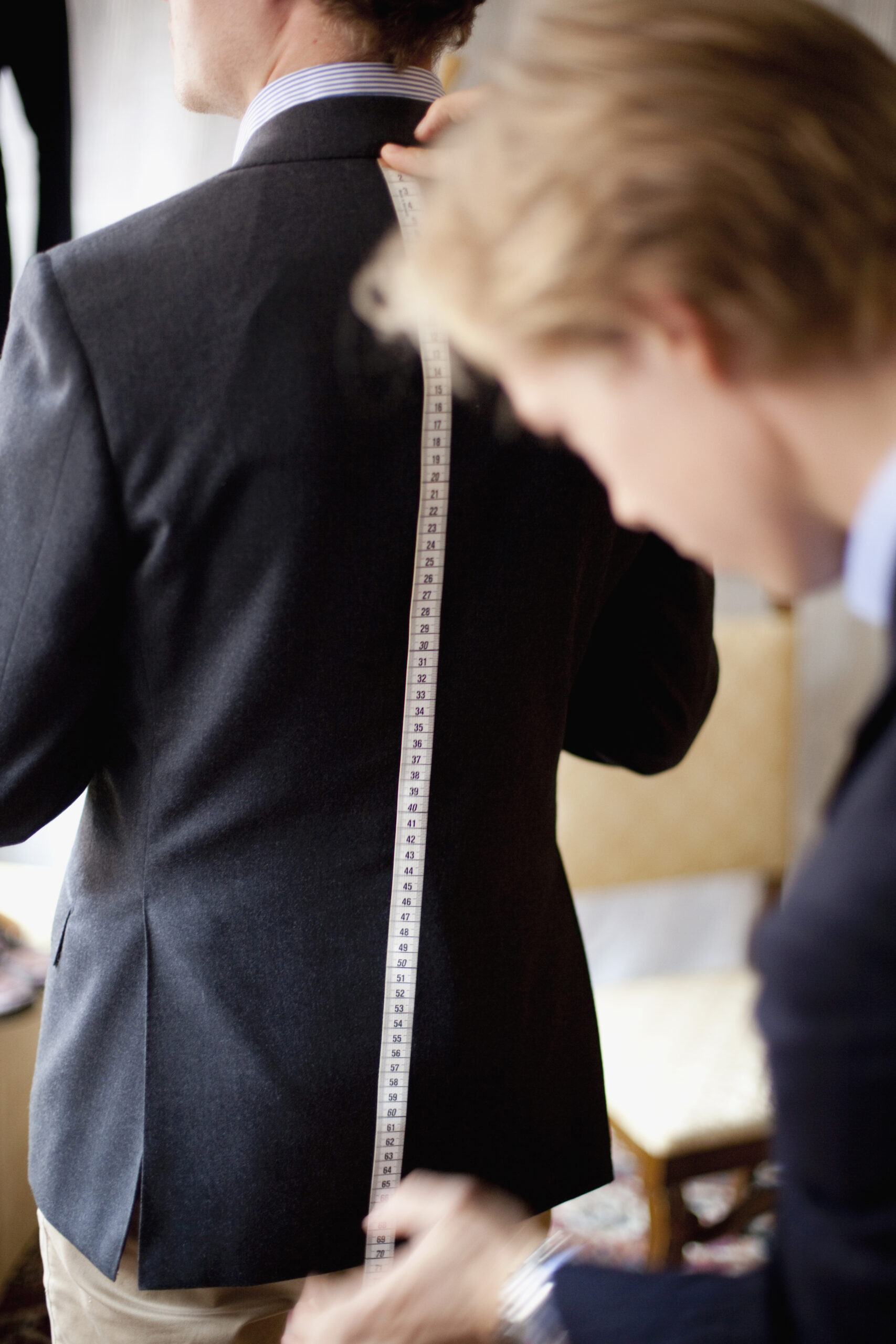 Fashion designer measuring male customer's back in clothing store